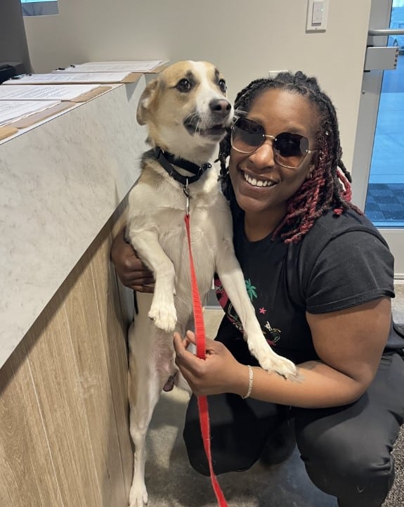 a black woman hugs a dog on a leash