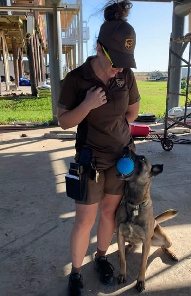 a dog with a ball in its mouth is sitting next to a girl