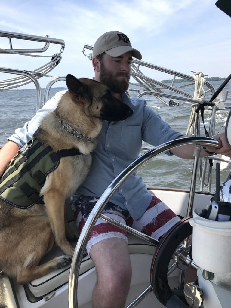 a German shepherd lies at the feet of a man