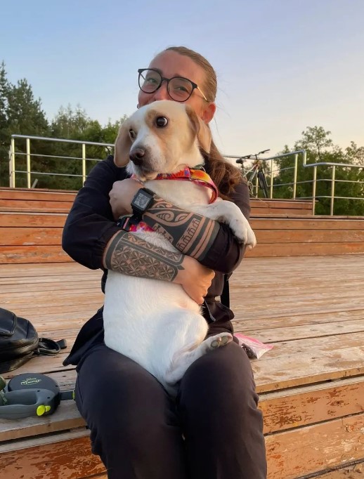 a girl holds a dog in her arms while sitting in the square