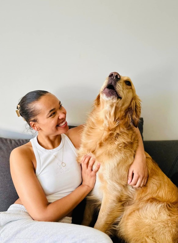 a golden retriever poses next to a girl