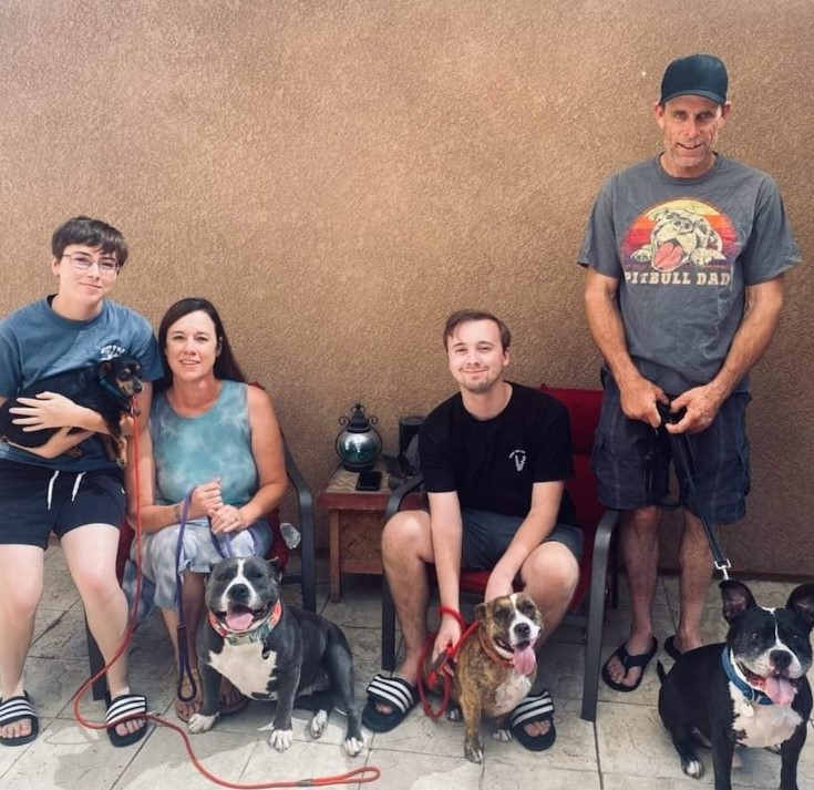 a happy family with their pit bulls on a leash