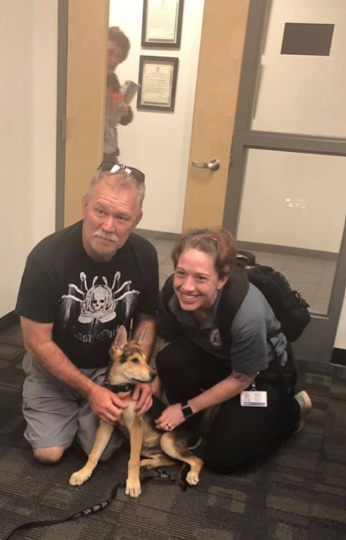 a man and a woman are photographed with a rescued dog