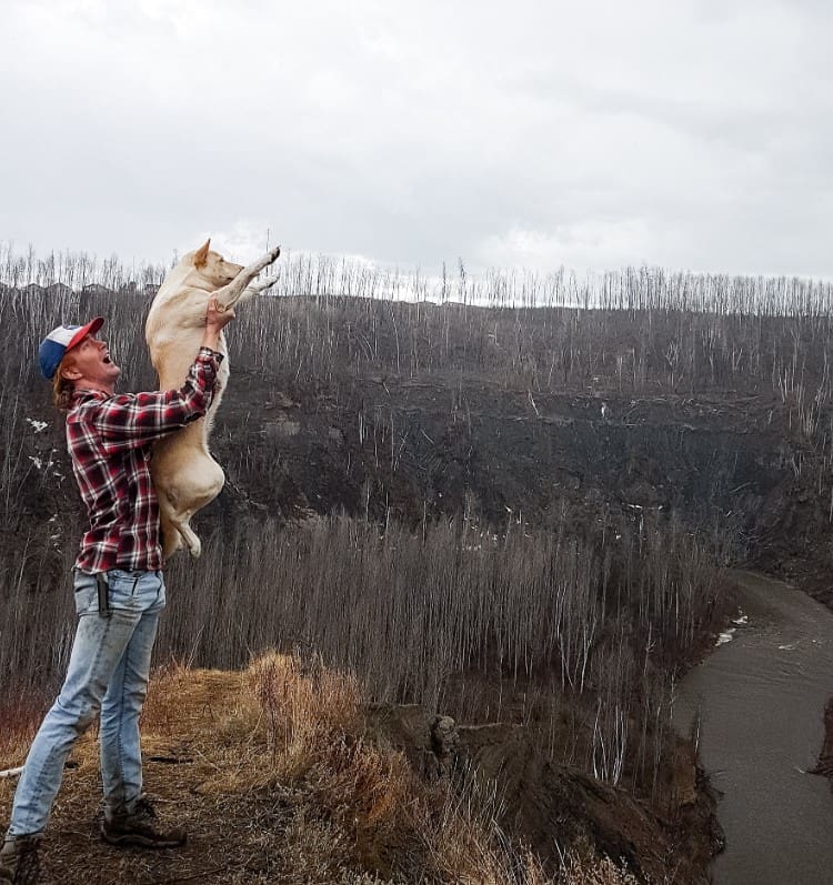 a man holds a dog in his arms in the forest