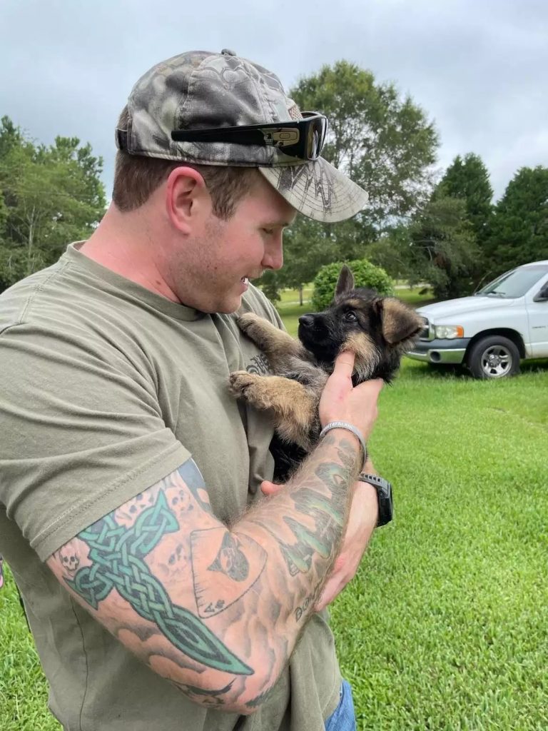 a man holds a puppy in his hands and caresses it