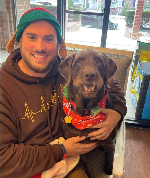 a man is sitting with a dog in his arms