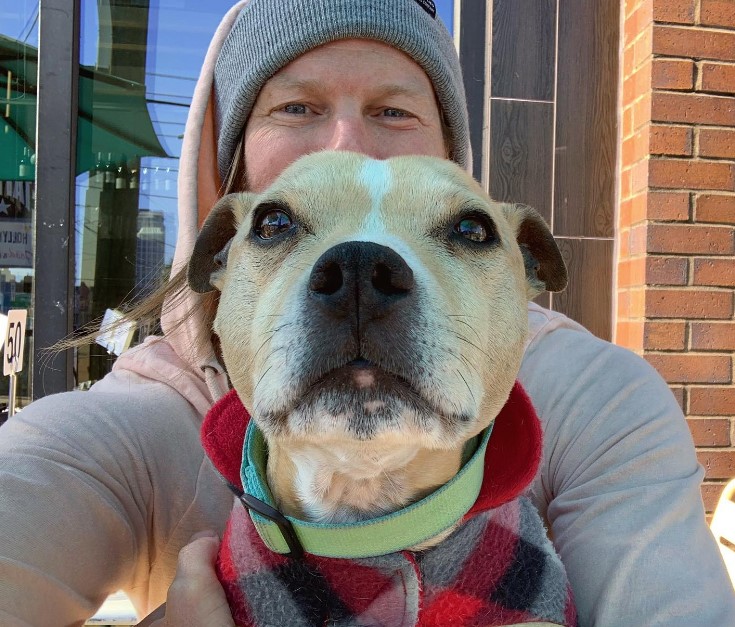 a man with a gray cap on his head with a dog