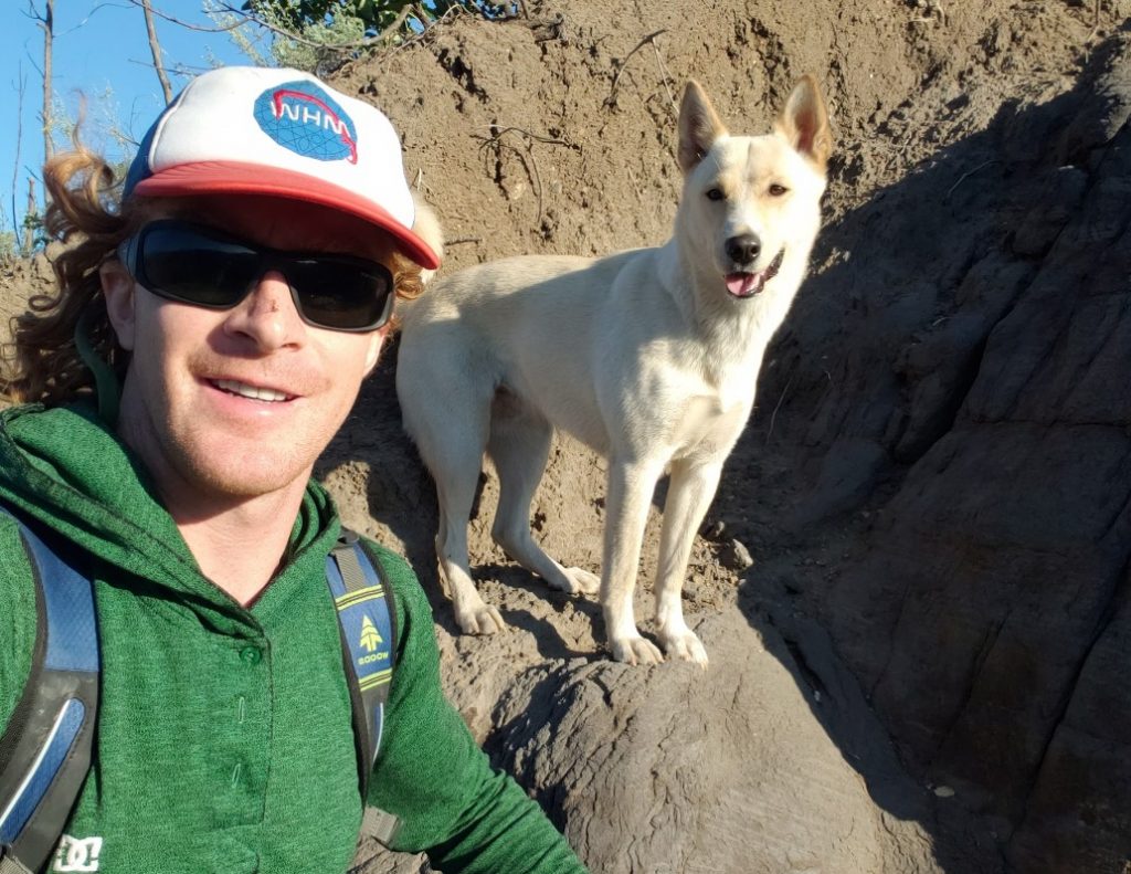 a man with his dog takes a picture on a rock