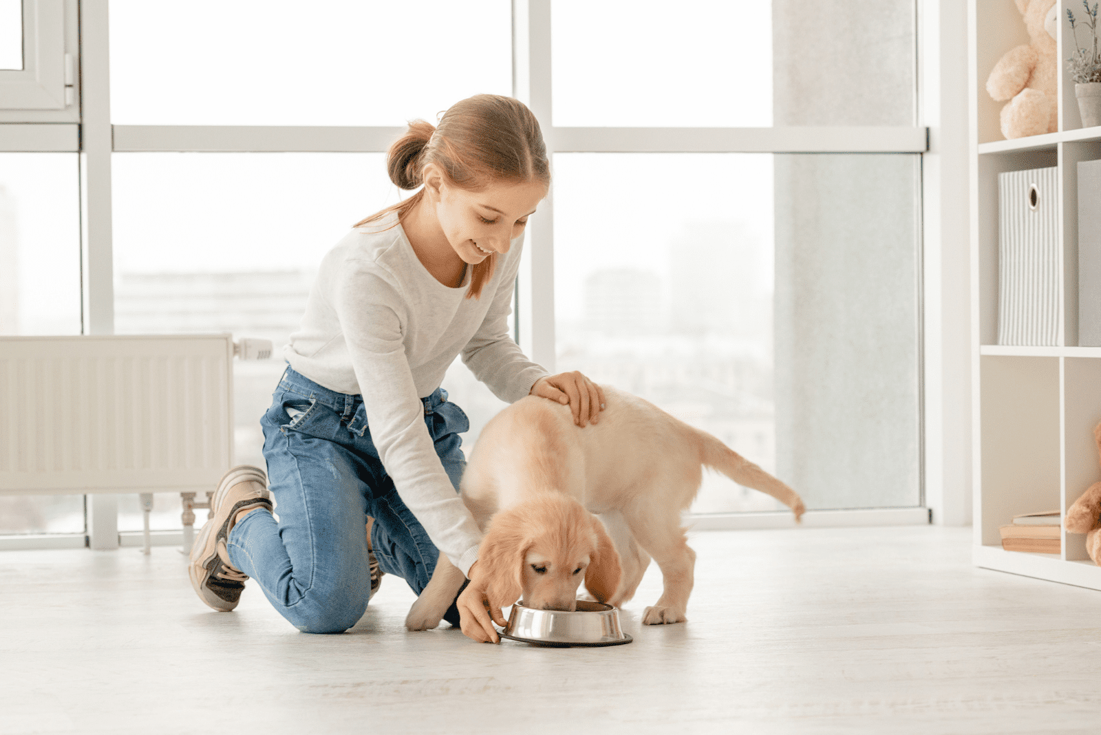 a smiling woman feeds a golden retriever