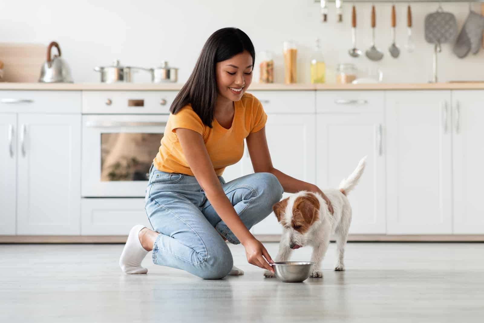 a smiling woman gives food to a dog