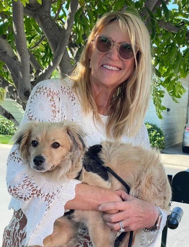 a smiling woman holds a puppy in her arms