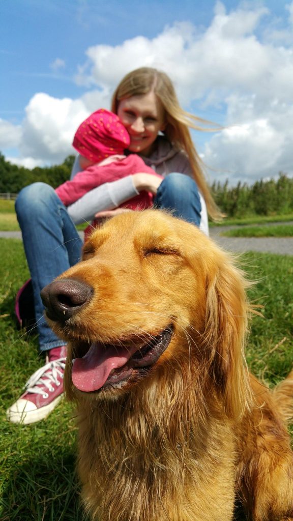 a woman with a child in her arms and a dog enters the frame