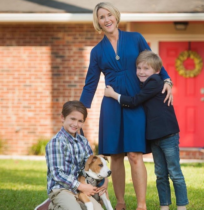 a woman with two sons and a dog takes a picture in the garden