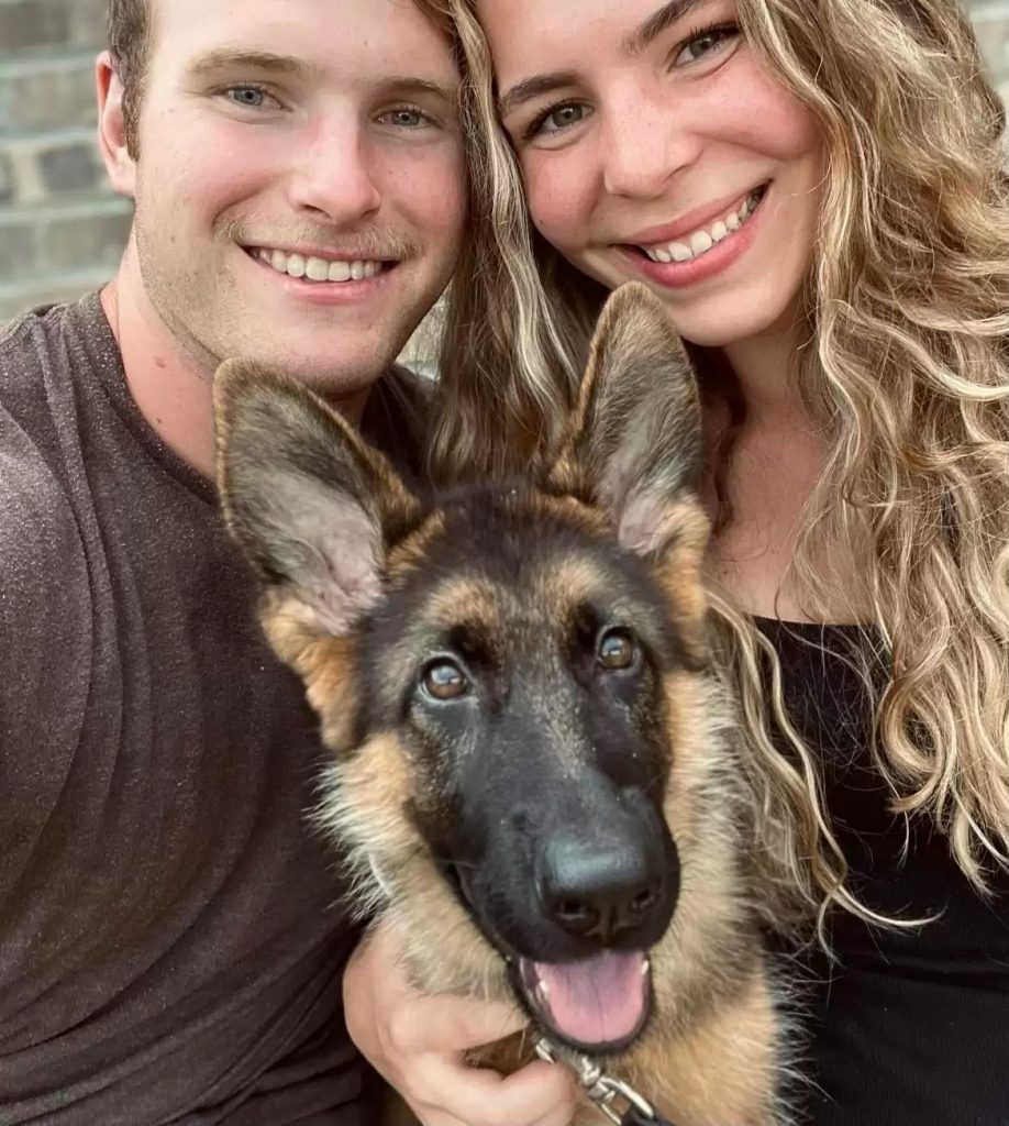 a young couple takes a picture with their dog