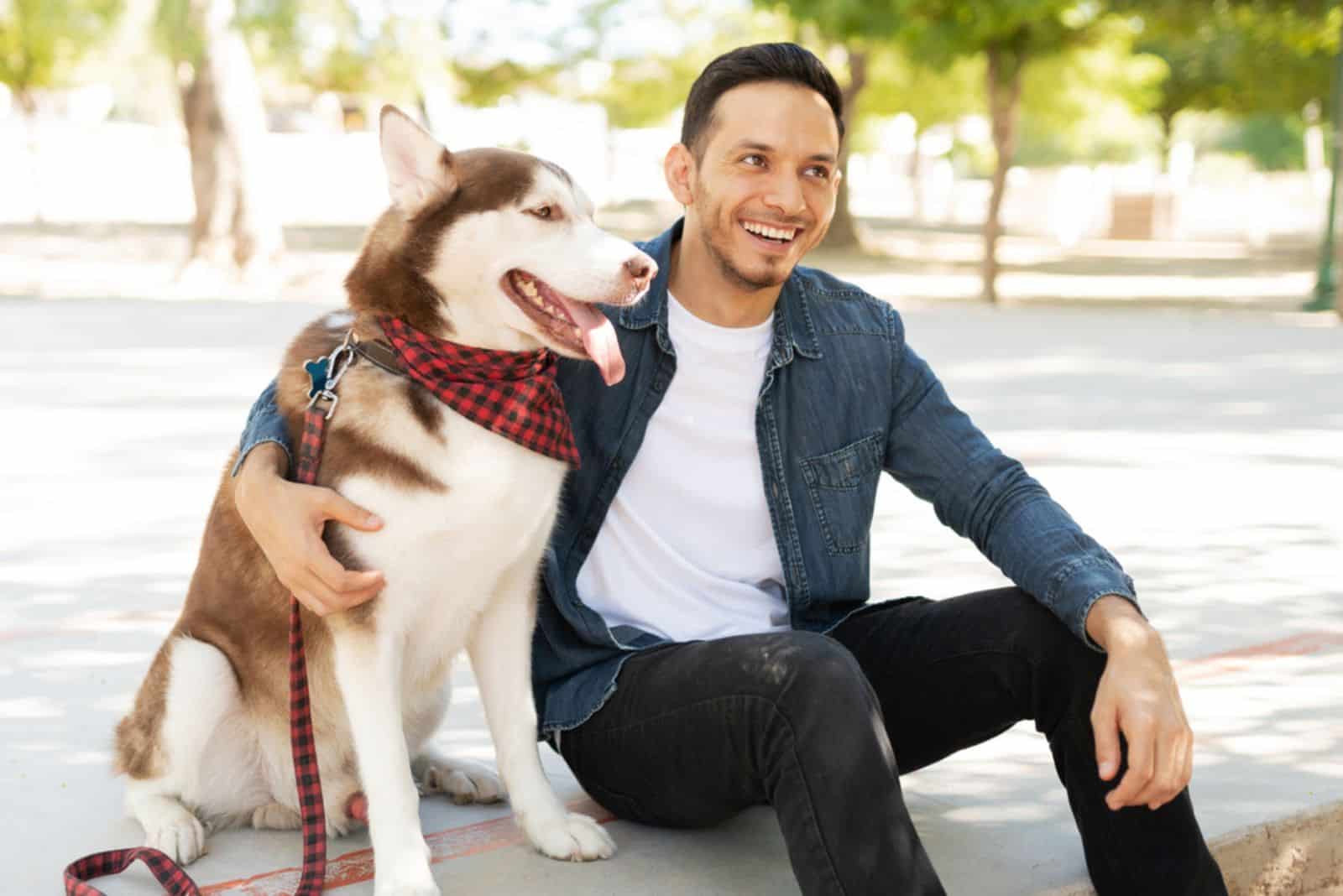 Attractive male dog owner laughing and embracing a beautiful husky