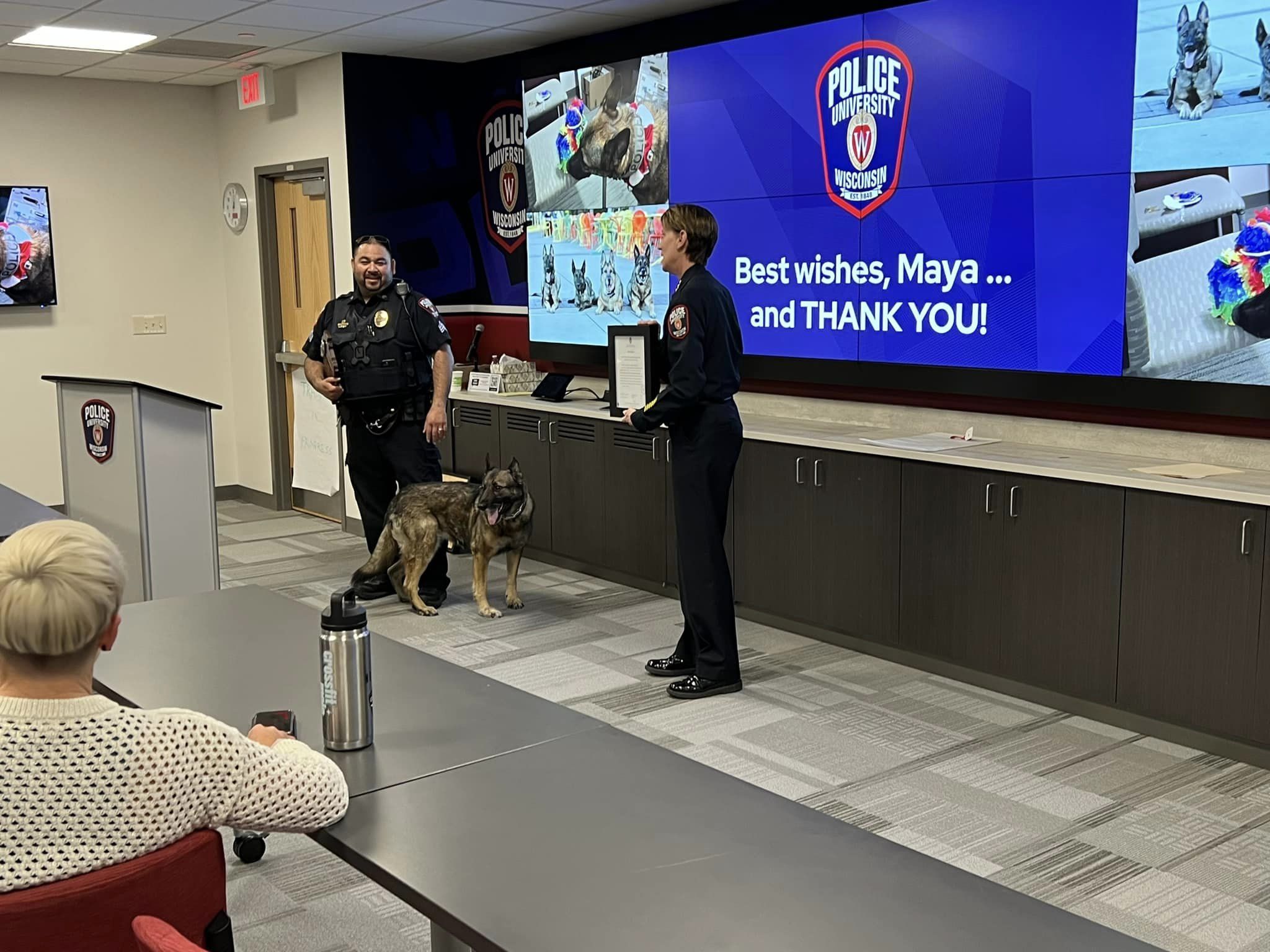 dog maya standing between two officers