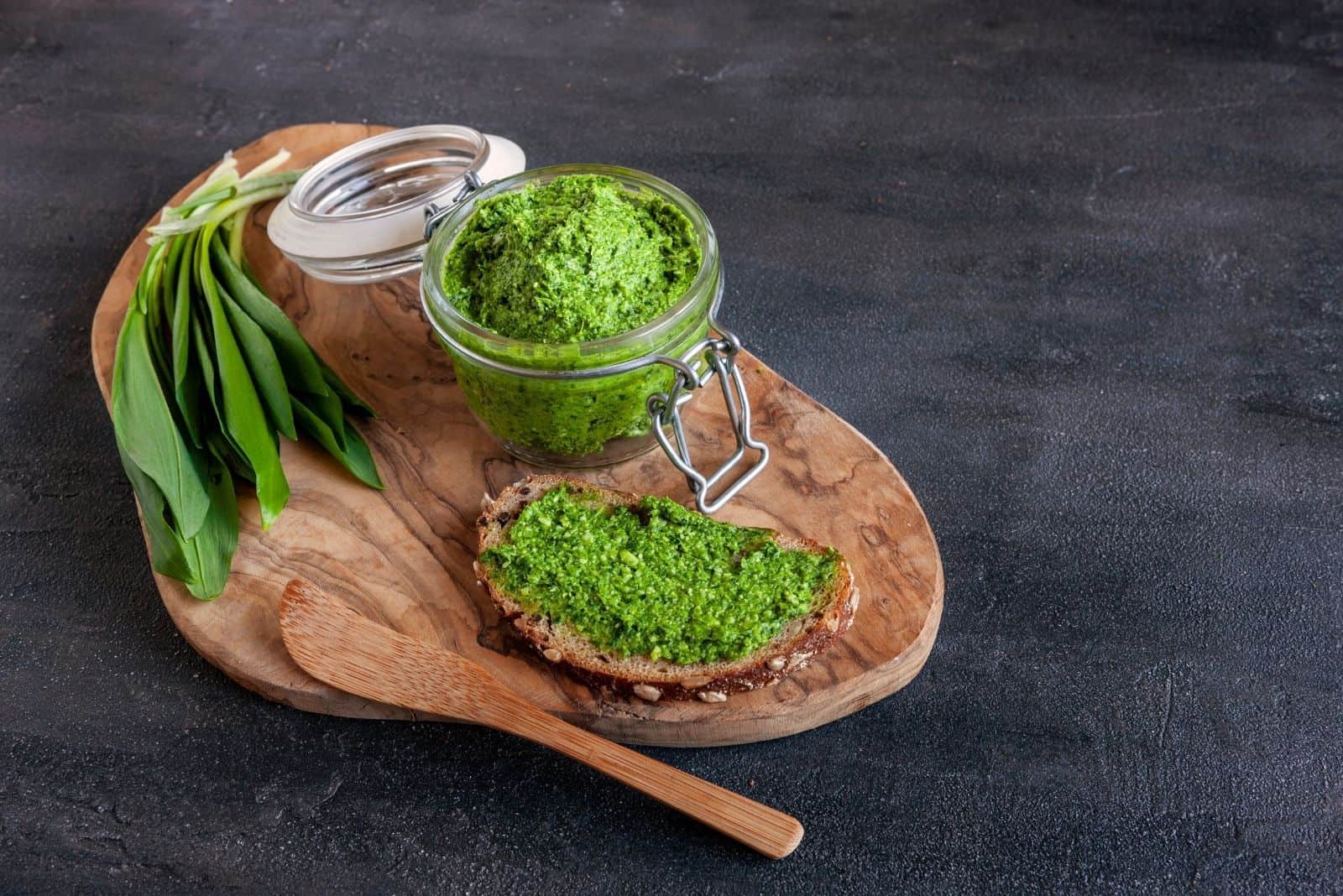 fresh homemade pesto with leaves on wooden plate and spoon