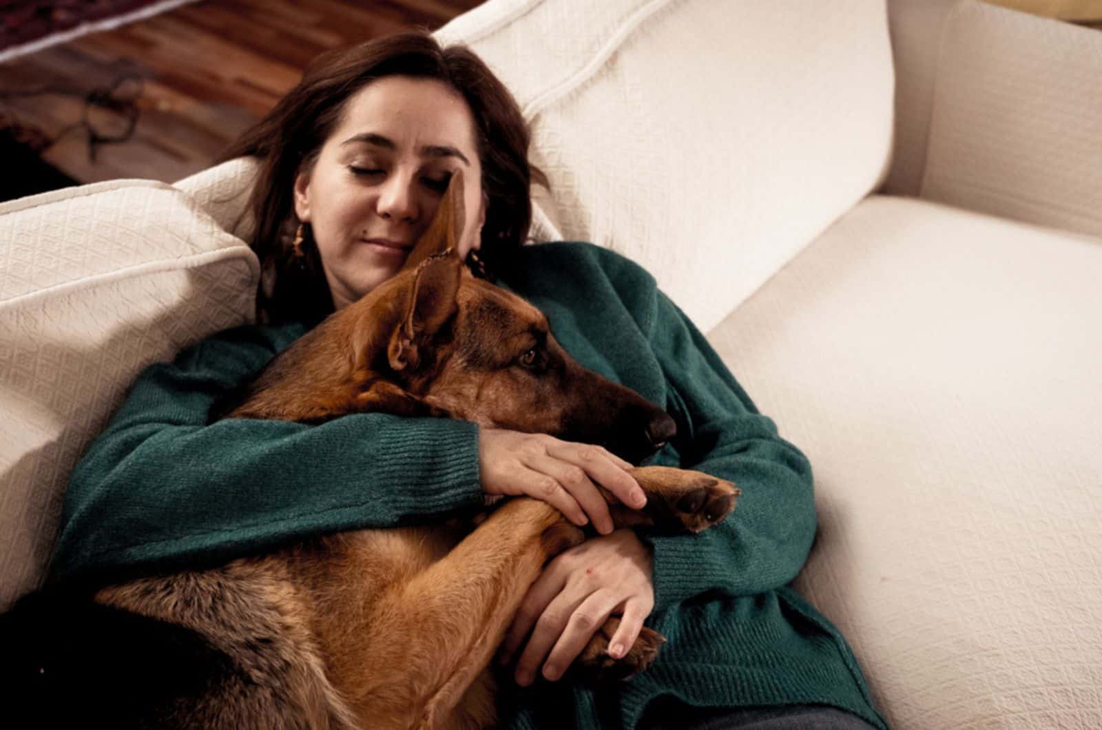 german shepherd dog lying on his owner on the couch