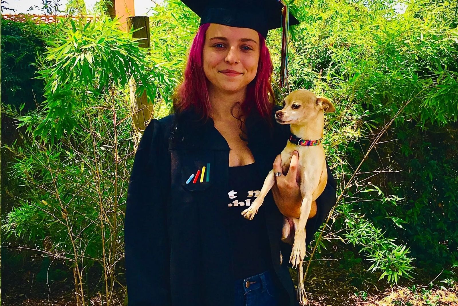 girl wearing cap and gown holding a dog