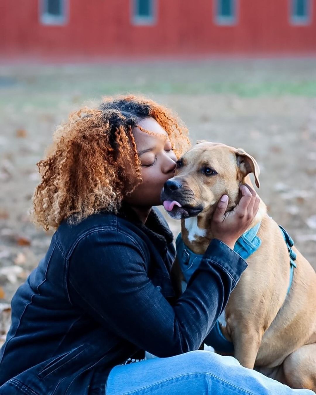 Girl with curly hair hugging a dog