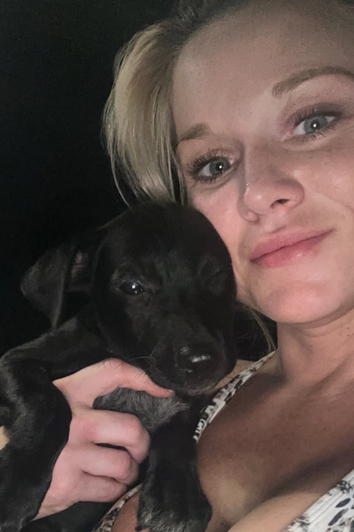 woman holding little black puppy