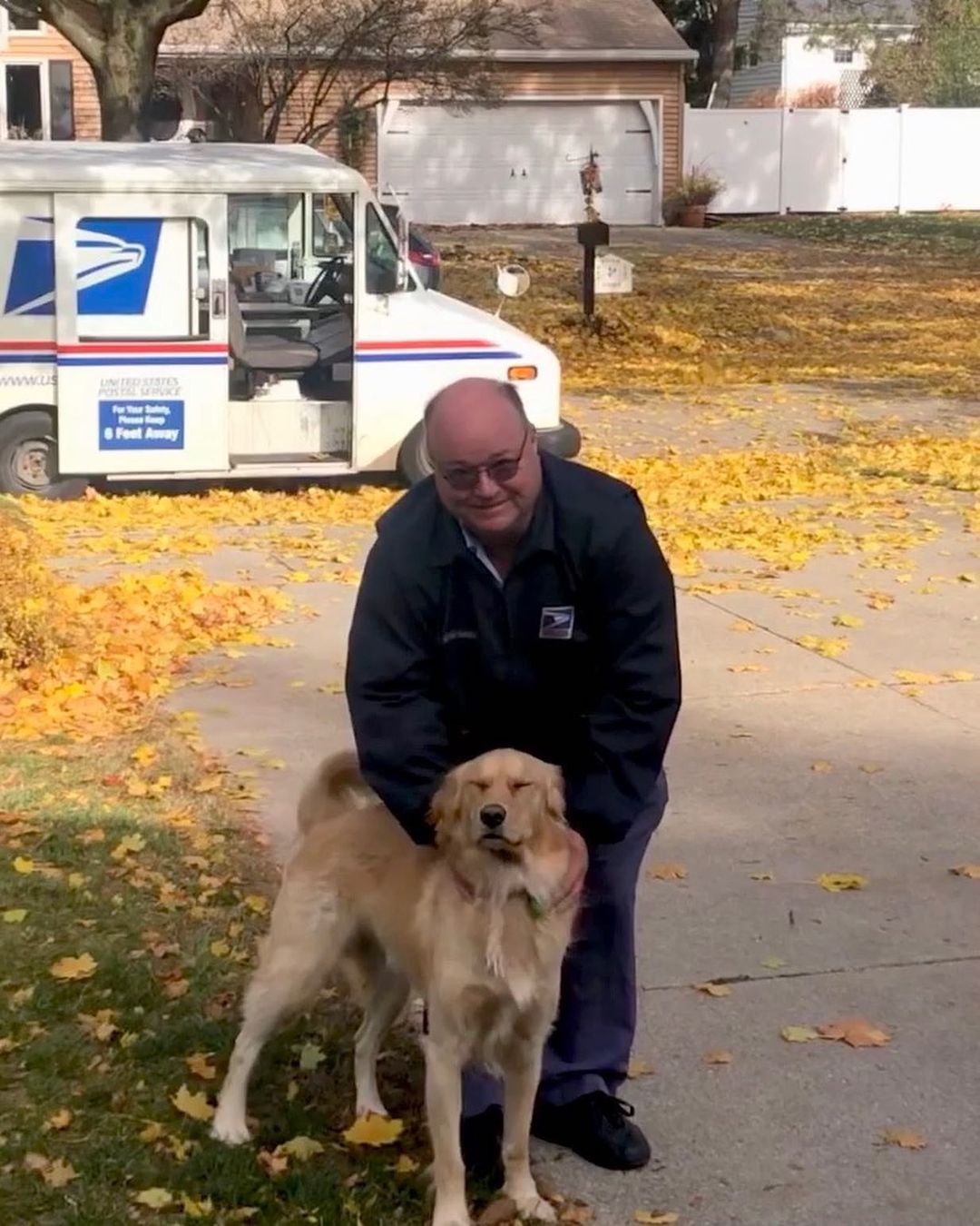 golden retriever and mailman posing for photo