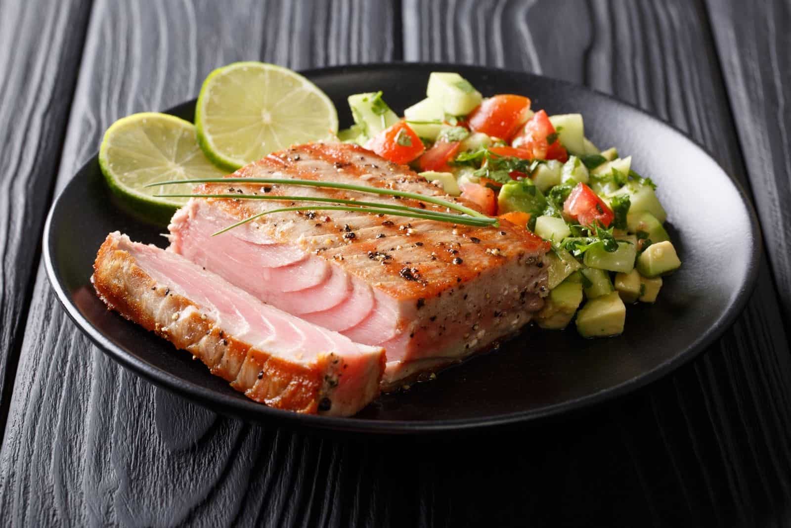 grilled tuna steak with pepper abd avocado cucumber salsa in close image