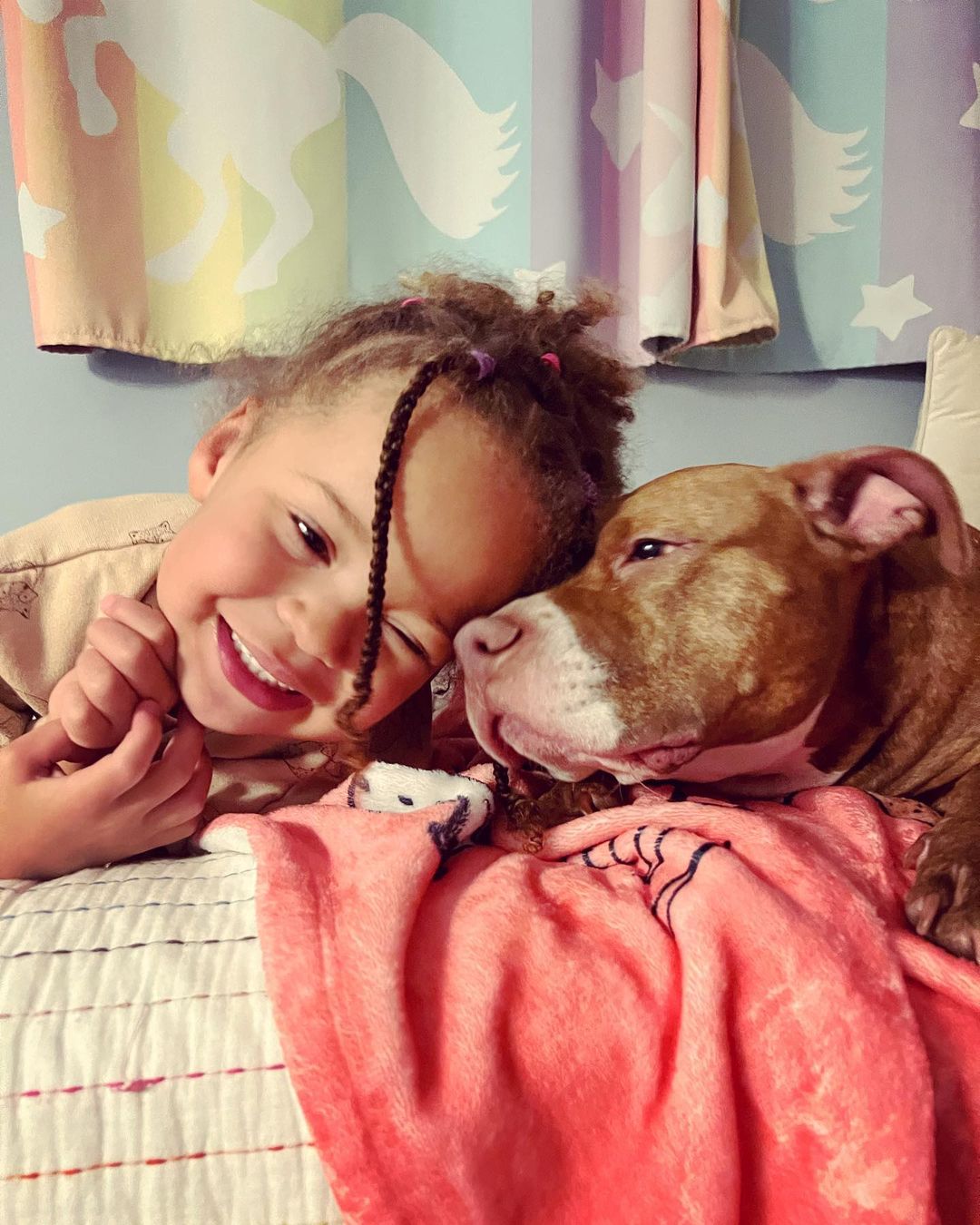 little girl and pitbull lying on bed