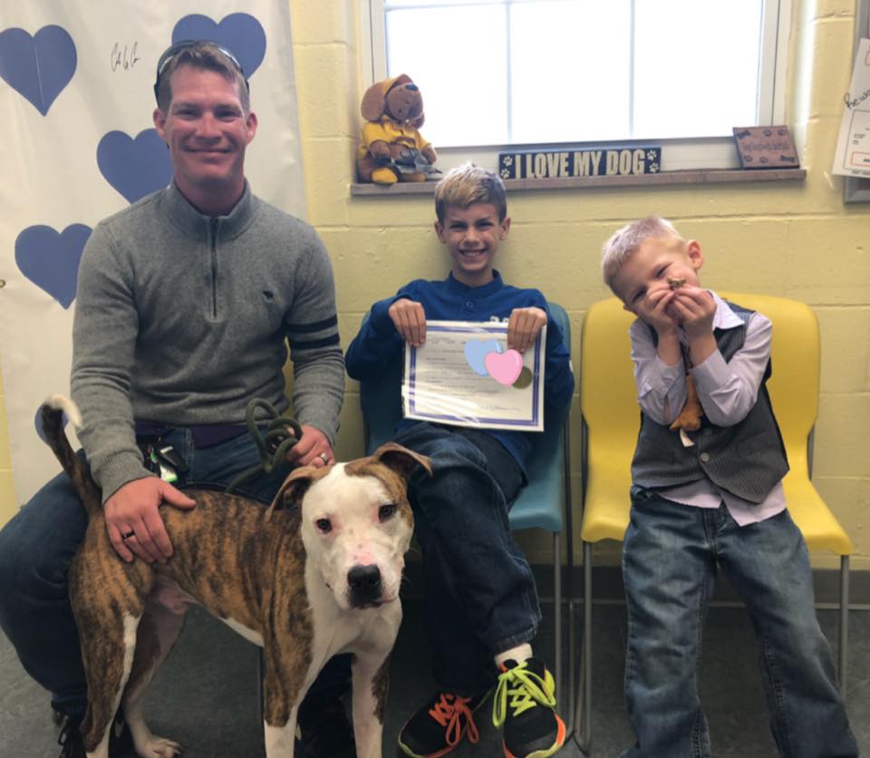 man and two boys sitting down with a dog in front of them