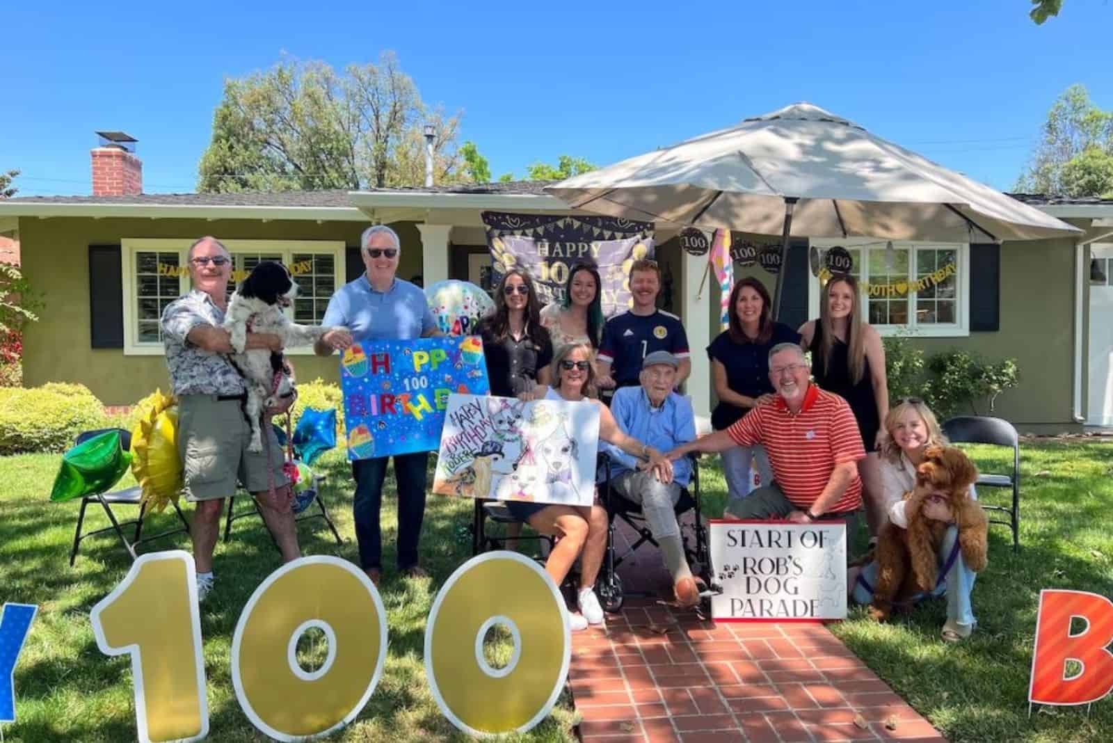 man celebrating 100th birthday with friends and dogs