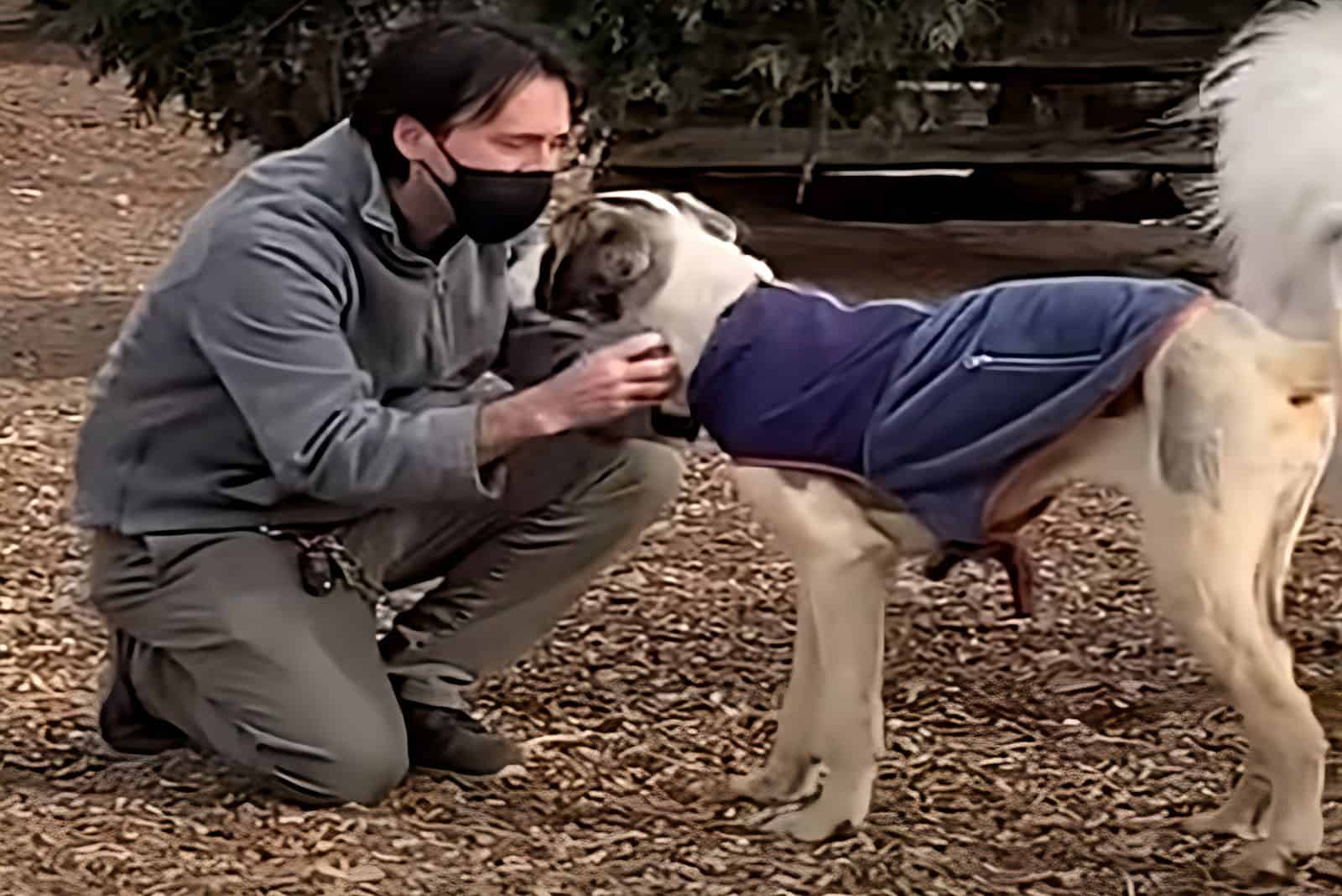 man cuddling dog in the park