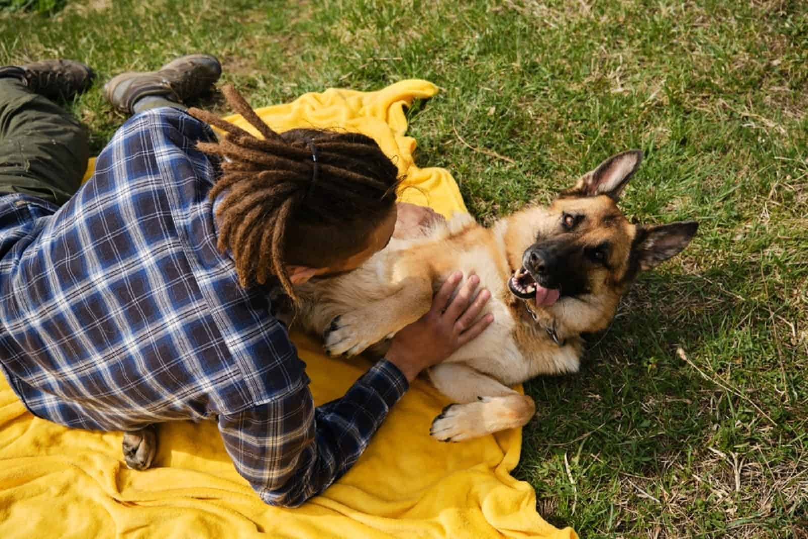 man cuddling his german shepherd dog lying on his back