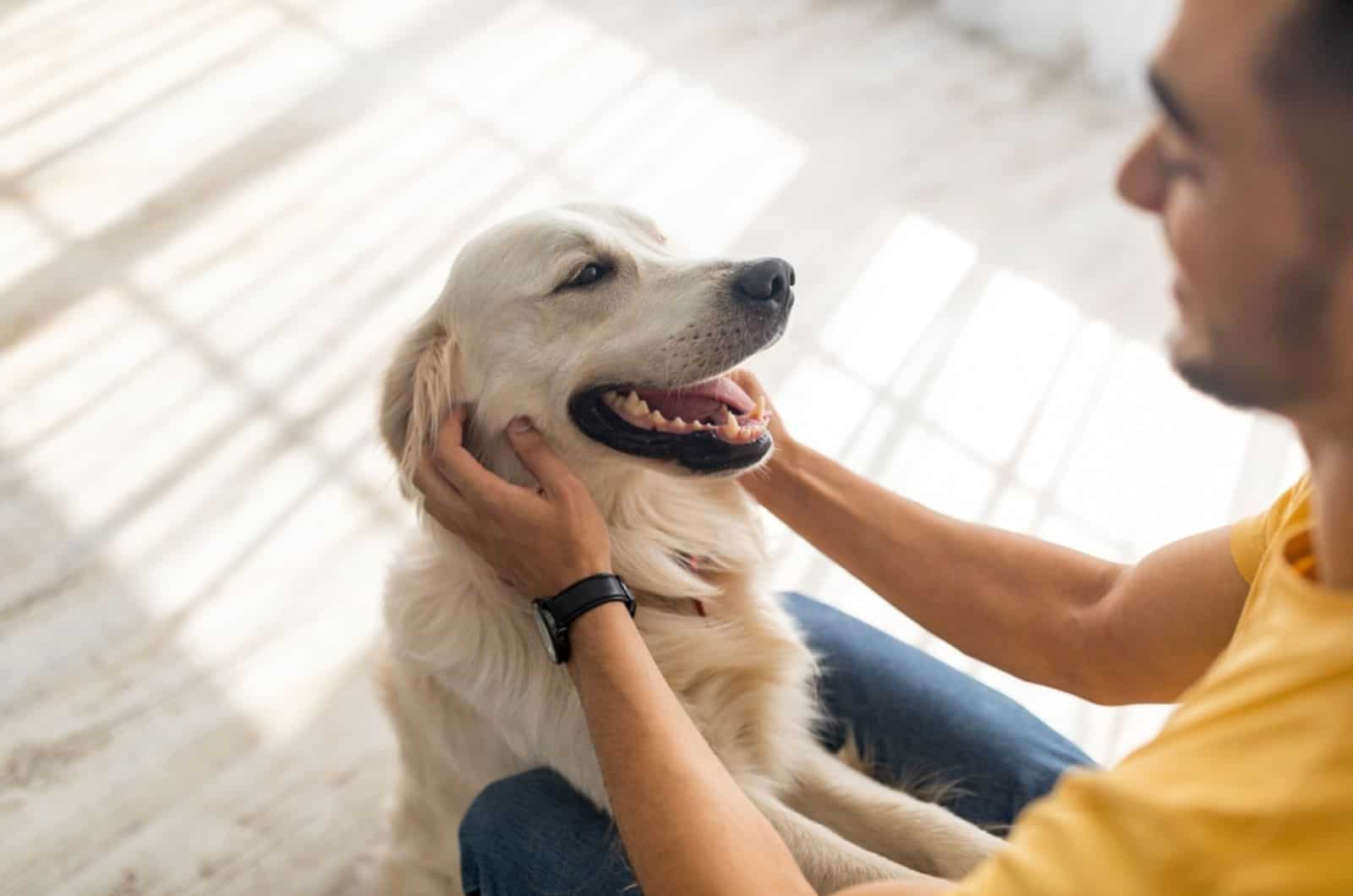 man cuddling his golden retriever indoors