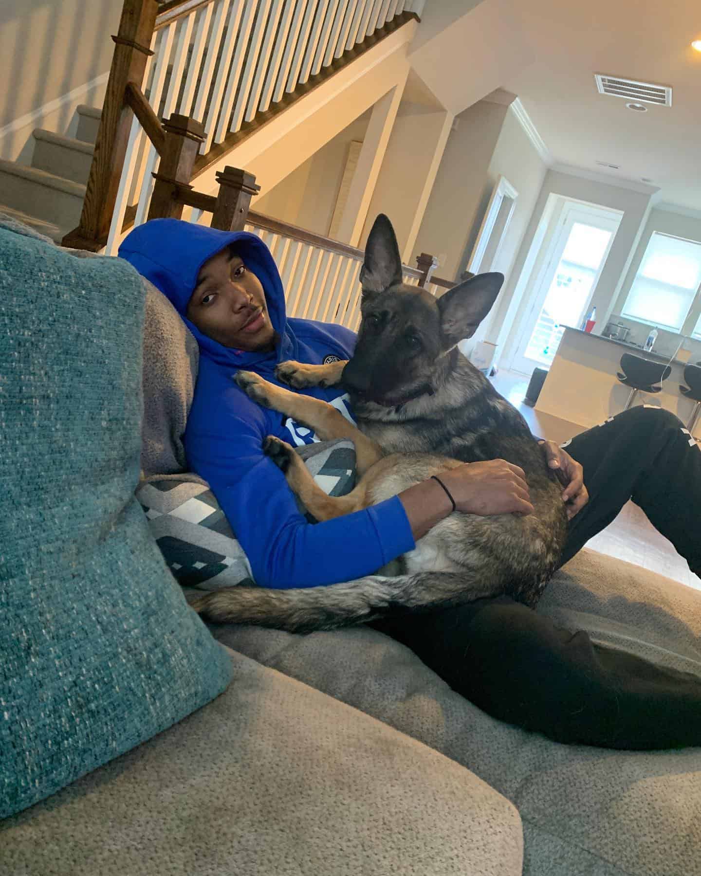man cuddling with german shepherd on the couch