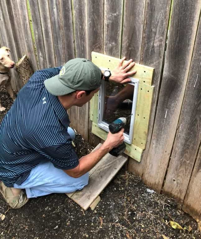 man fixing fence for dog hole