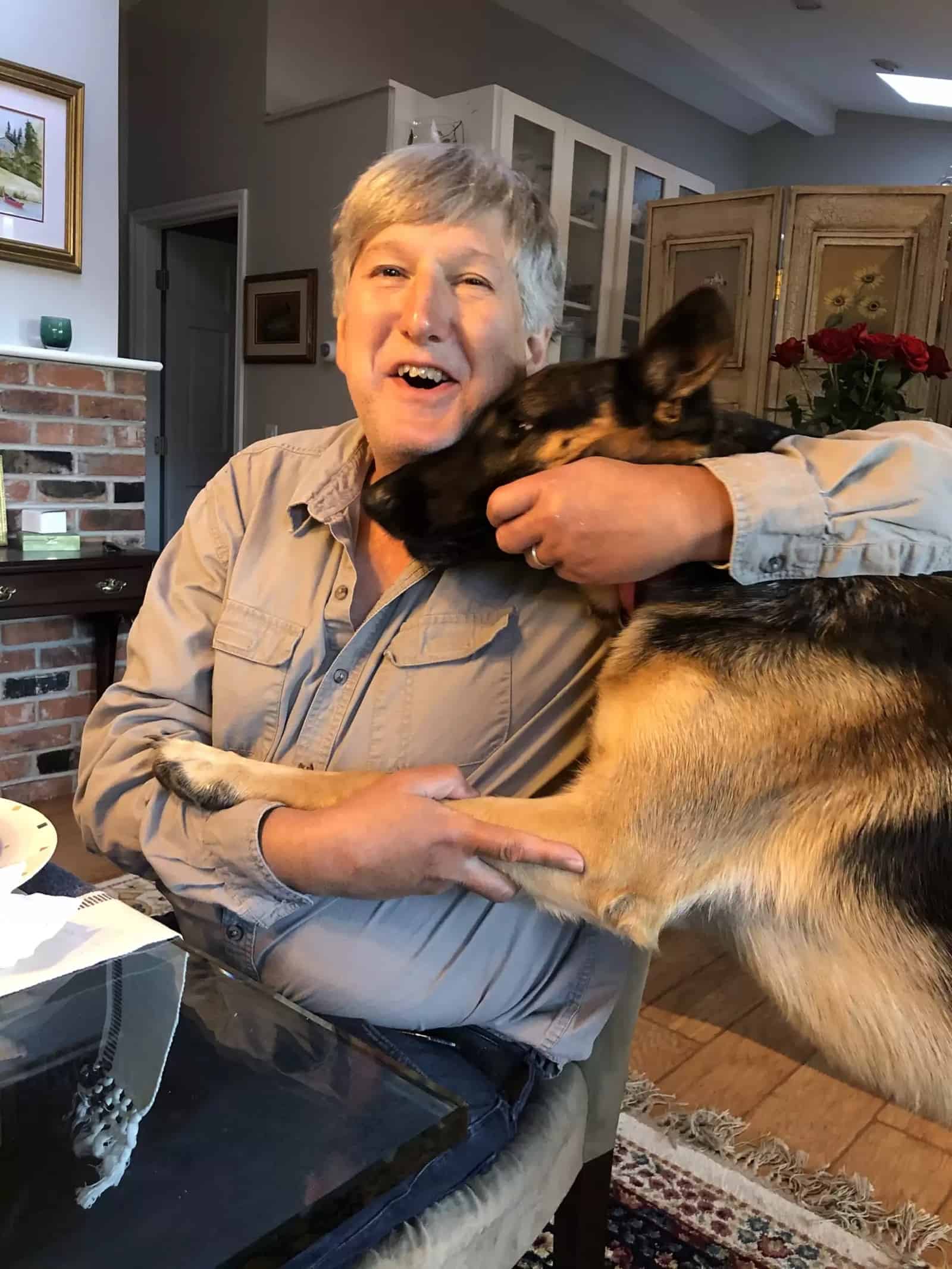 man hugging his german shepherd dog at home