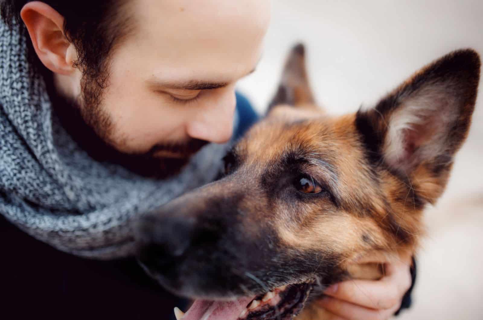 man hugging his german shepherd outdoors