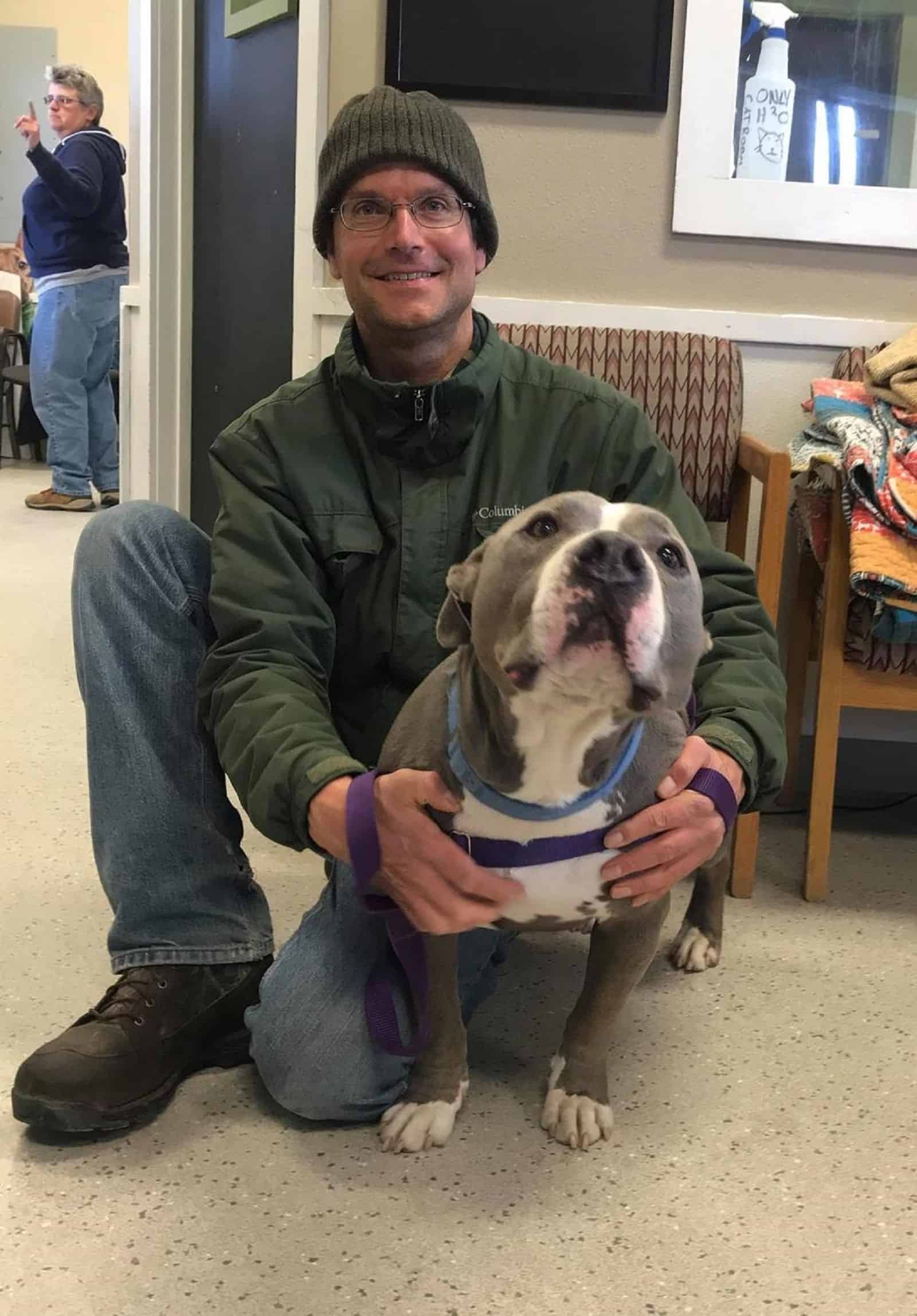 man sitting beside pitbull dog and embracing him