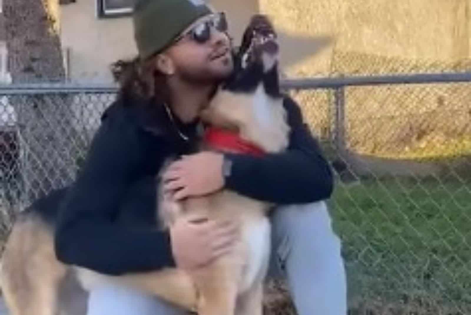 man with sunglasses hugging german shepherd