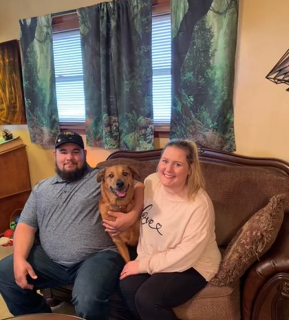 owners and dog sitting on the sofa