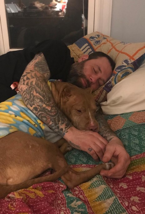 portrait of a man and a dog sleeping together