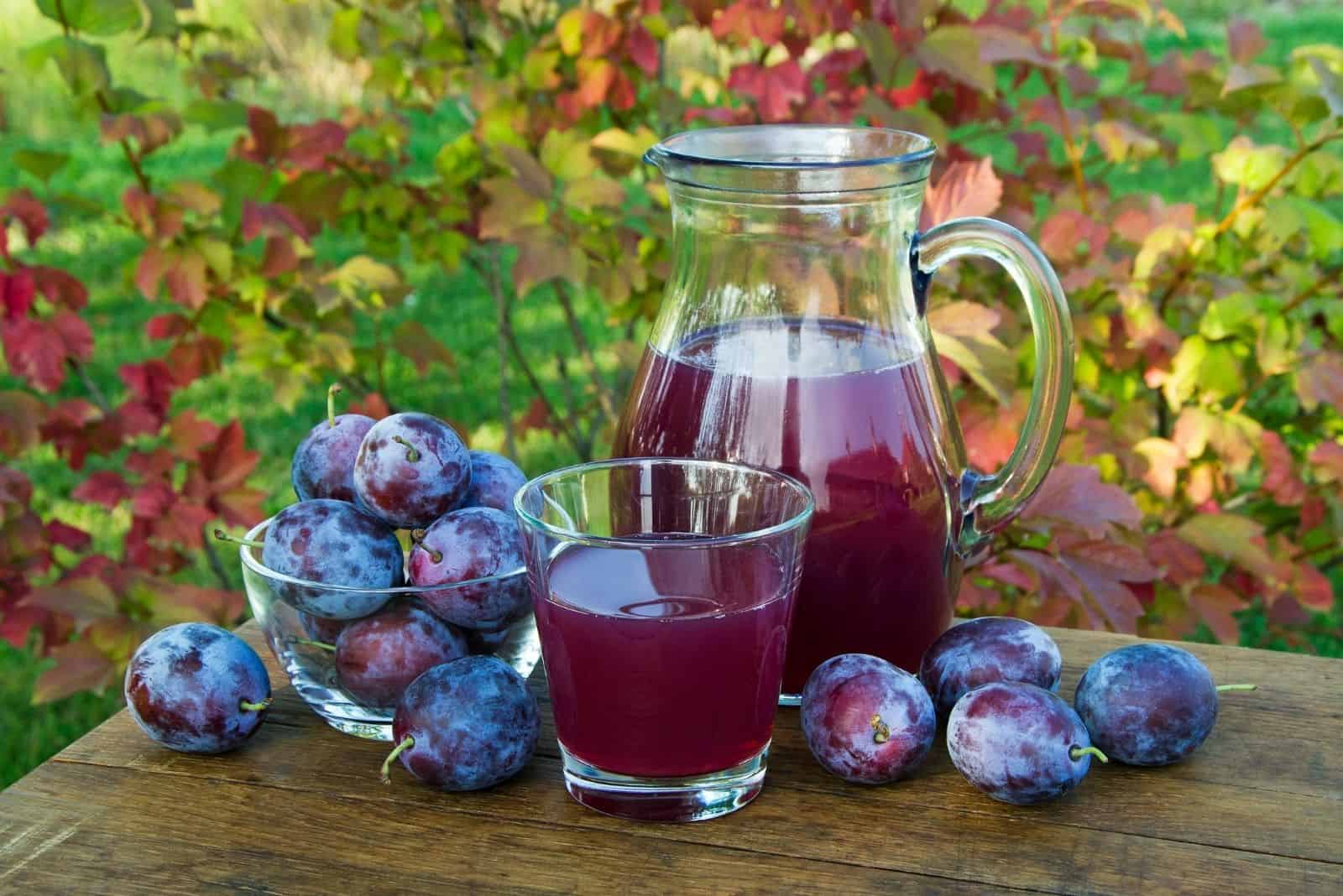 prune juice in the carafe with fresh plums on the glass