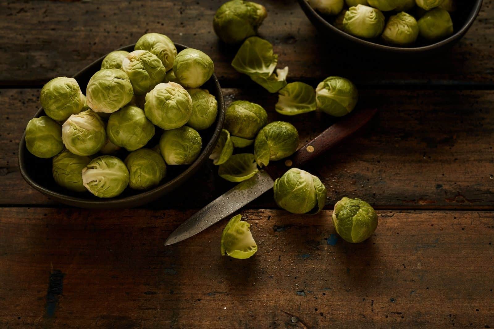 raw brussel sprouts with a knife on top of the table