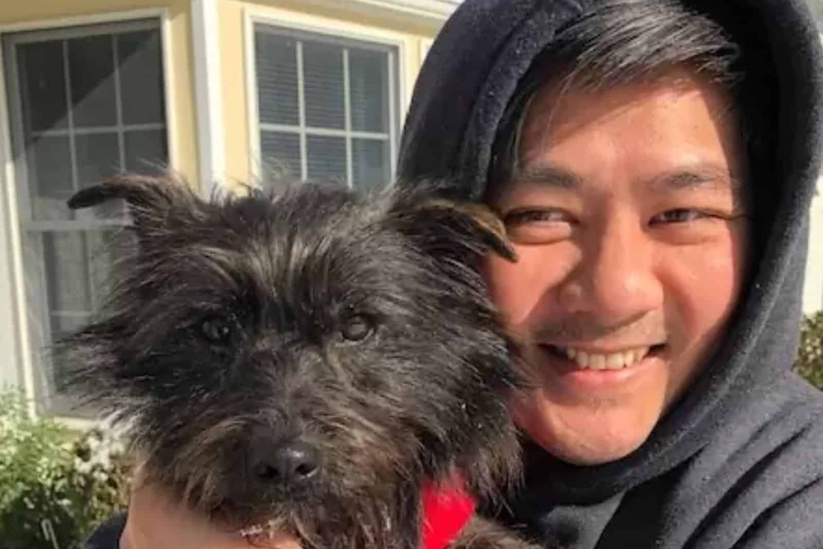 smiling man hugging a dog in the yard