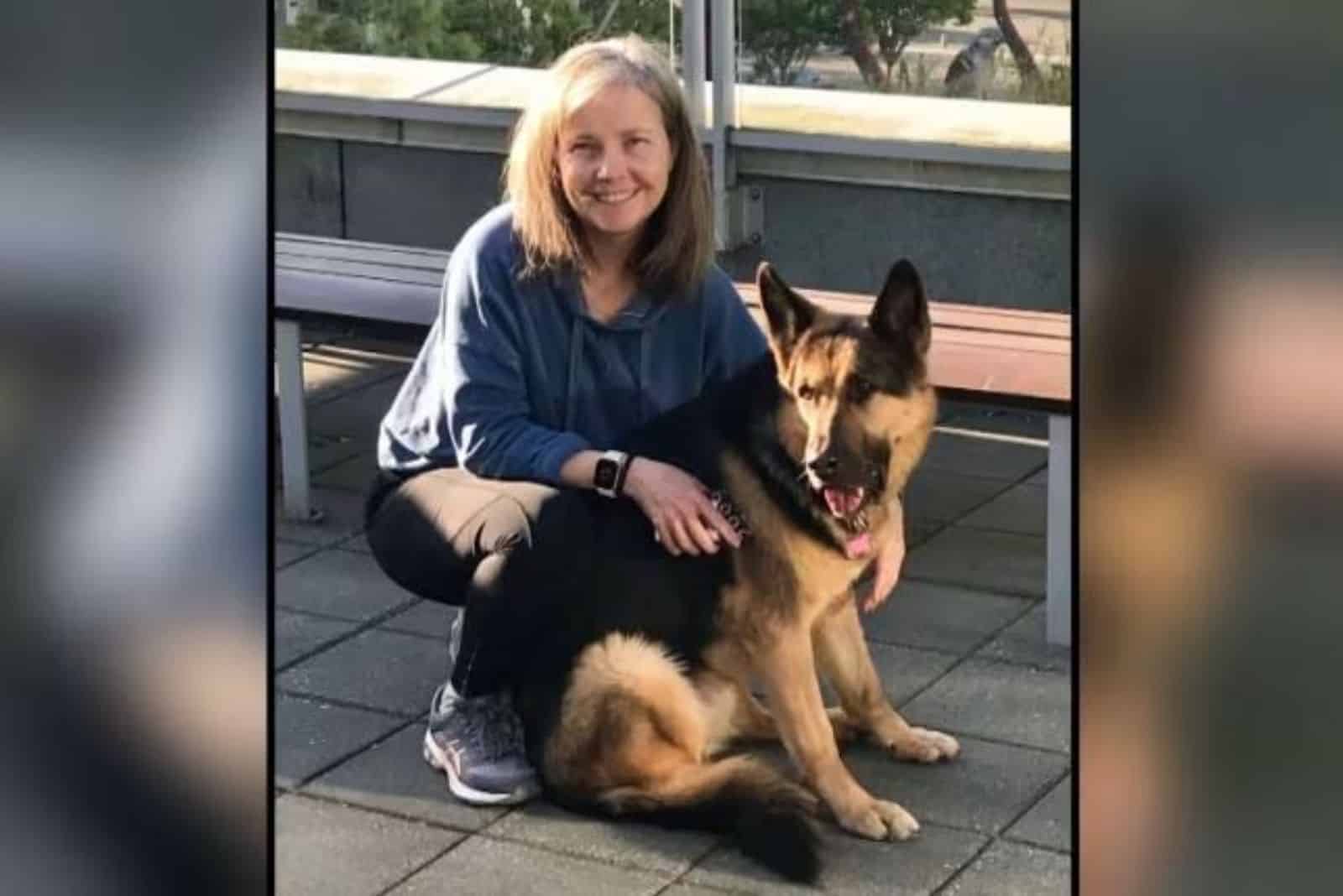 smiling woman embracing german shepherd dog outdoors