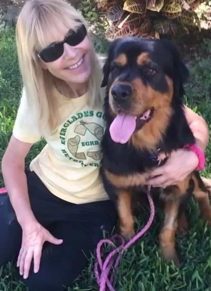 smiling woman embracing rottweiler dog in the garden