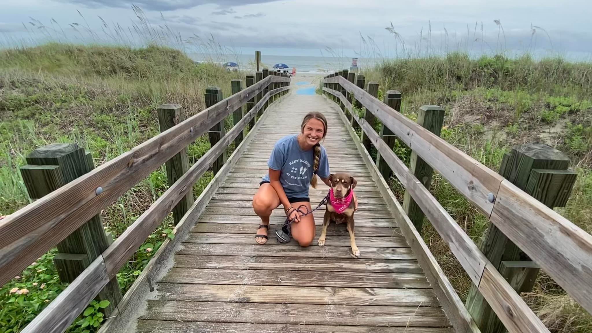 smiling woman posing with dog on the beach porch
