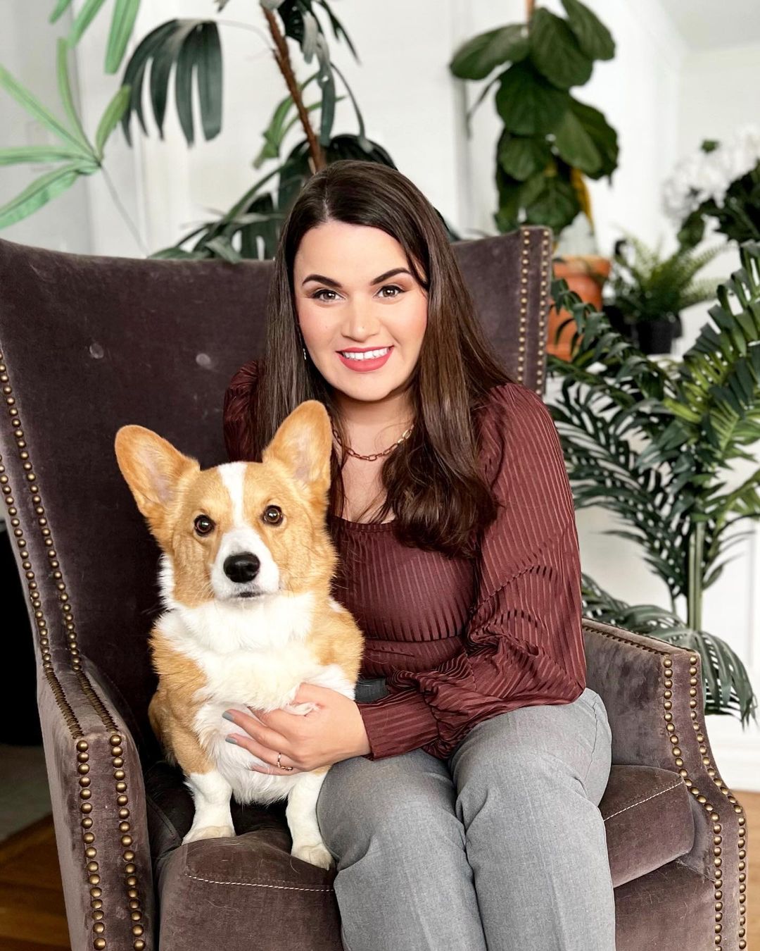 smiling woman with corgi on sofa