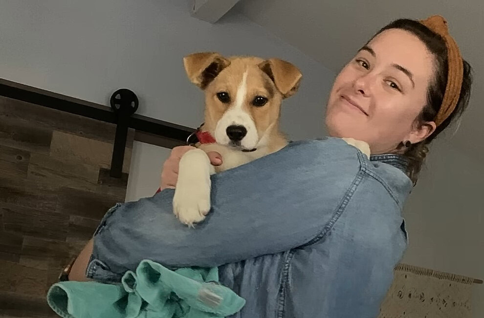 smiling woman with dog in arms posing