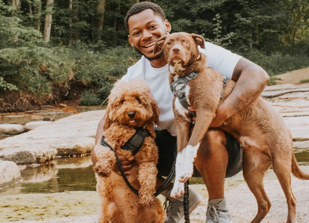 the smiling man is holding a goldendoodle and another dog in his arms